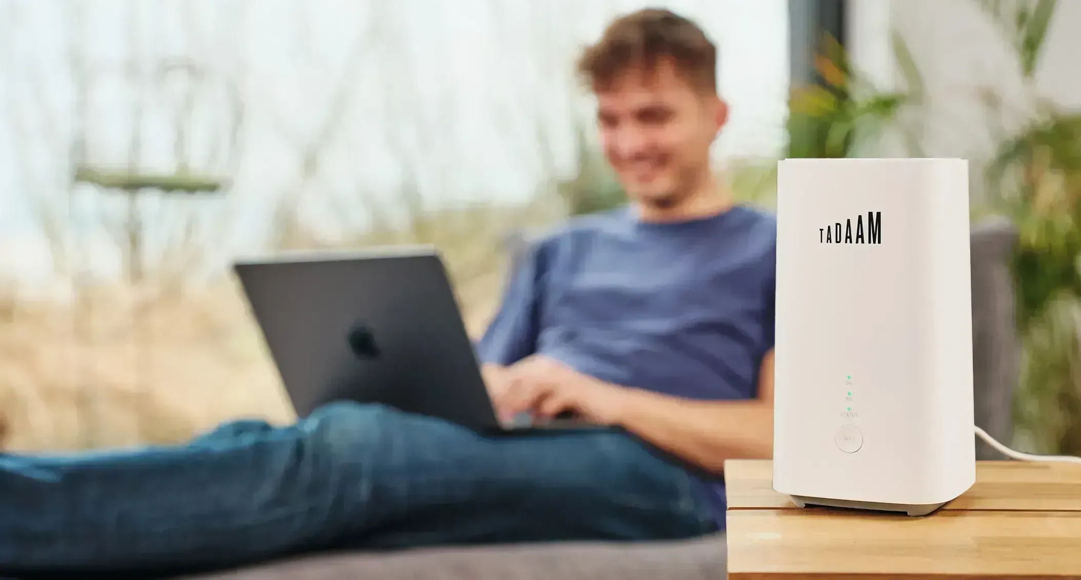 An image of the TADAAM Modem with a person in the background working on a laptop